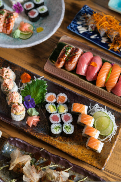 From above of tasty assorted sushi and rolls with fresh fish served on trays with decorative flowers in light cafe